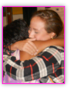 Two young people embracing warmly at a program event.
